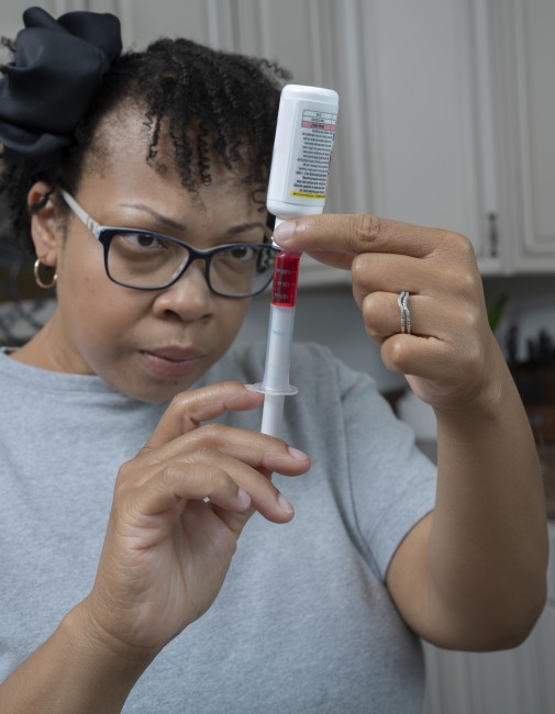 African American/Black woman measuring liquid medicine with syringe