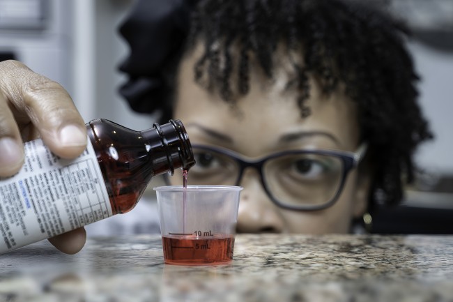 African American/Black woman measuring liquid medicine