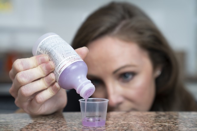 Caucasian/White woman measuring liquid medicine
