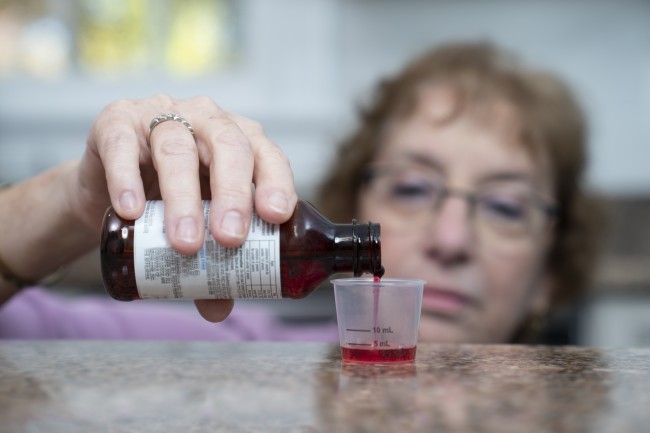 Caucasian/White woman with glasses measuring liquid medicine