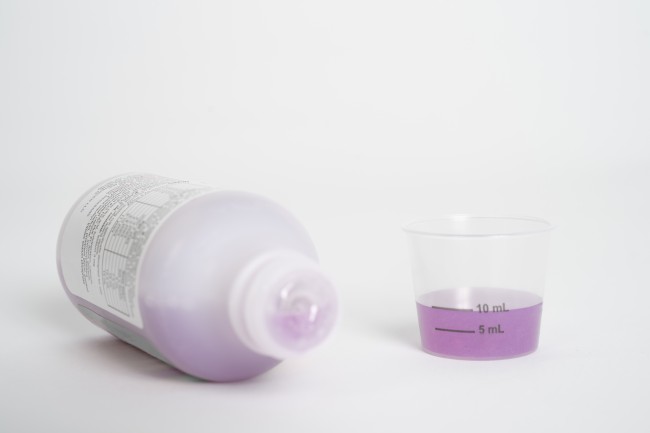 Medicine bottle and dosing cup with purple liquid medicine
