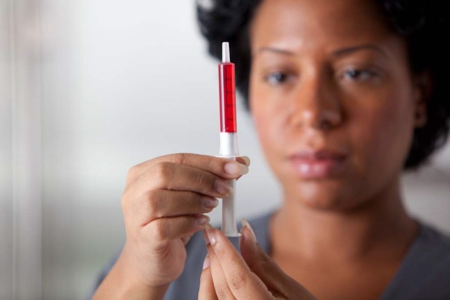 African American/Black woman measuring medicine with dosing syringe