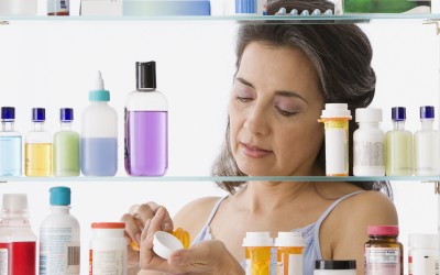 Hispanic woman measuring out medicine in front of a medicine cabinet