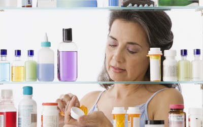 Hispanic woman measuring out medicine in front of a medicine cabinet Hispanic woman measuring out medicine in front of a medicine cabinet