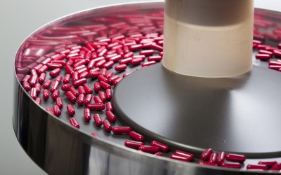 red capsules being sorted in a circular hopper