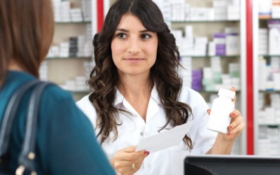 Pharmacist with long dark hair assisting customer in dark green shirt Pharmacist with long dark hair assisting customer in dark green shirt