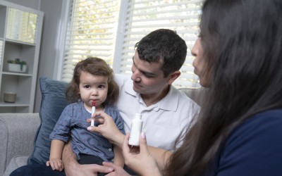 Racially ambiguous man and woman giving racially ambiguous toddler medicine