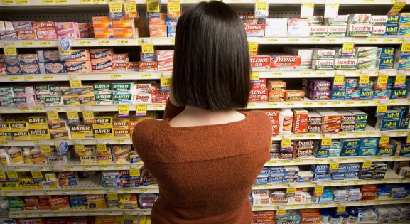 Woman in store aisle looking at OTC pain medications