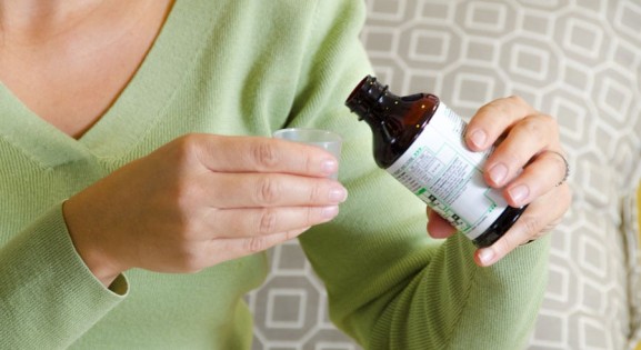 woman in green shirt measuring liquid medicine