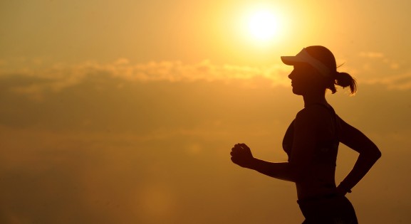 woman in hat running at sunset