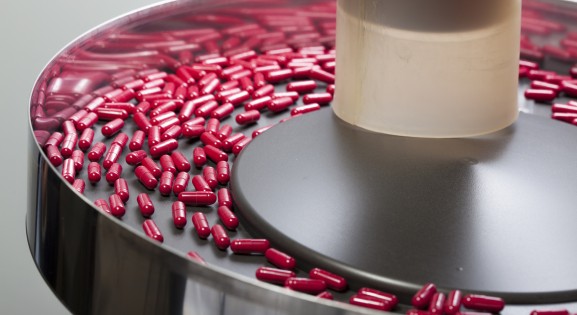 red capsules being sorted in a circular hopper