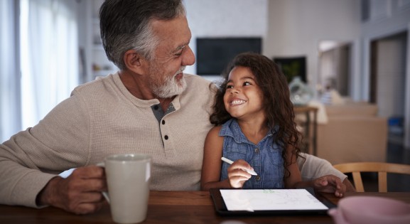 Happy Latinx grandfather with mug and granddaughter