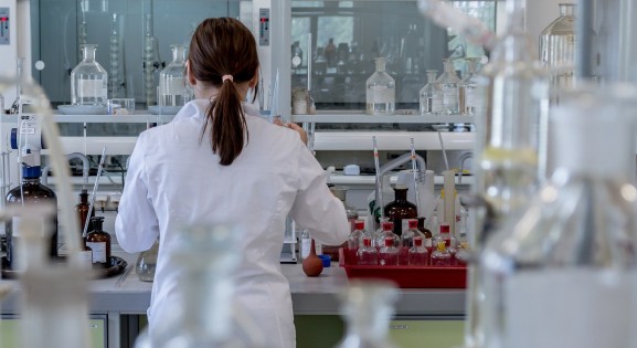 scientist with long dark hair in a lab facing away