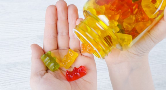 Child Holding Multicolored Gummy Vitamins