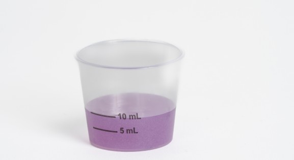 Dosing cup with purple liquid medicine
