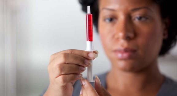 African American woman measuring medicine with dosing syringe