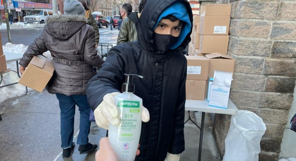 Young person giving hand sanitizer away