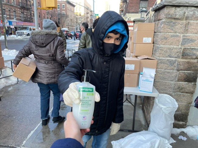 Young person giving hand sanitizer away